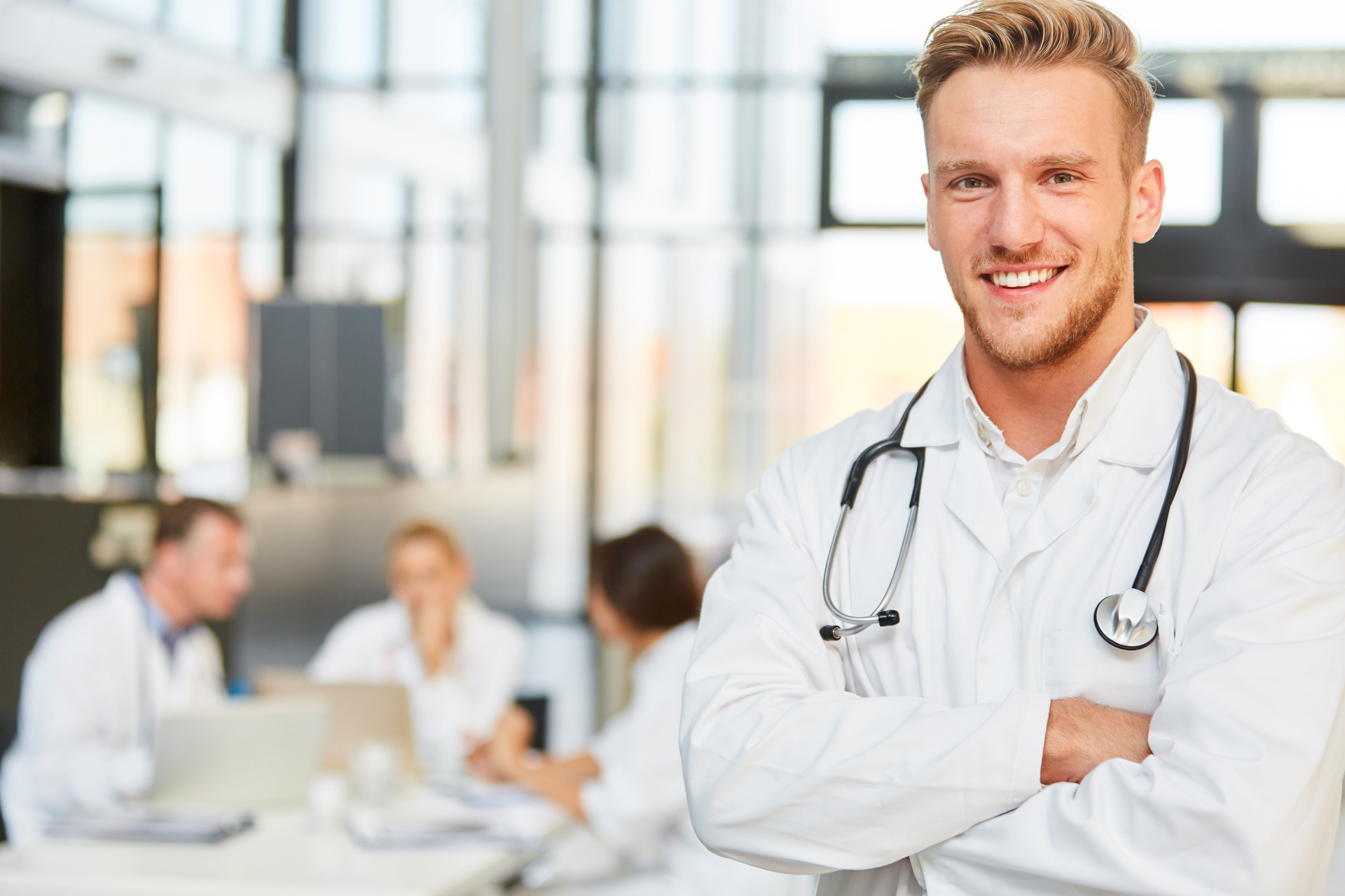 Lächelnder junger Facharzt oder Assistenzarzt Lächelnder junger Facharzt oder Assistenzarzt